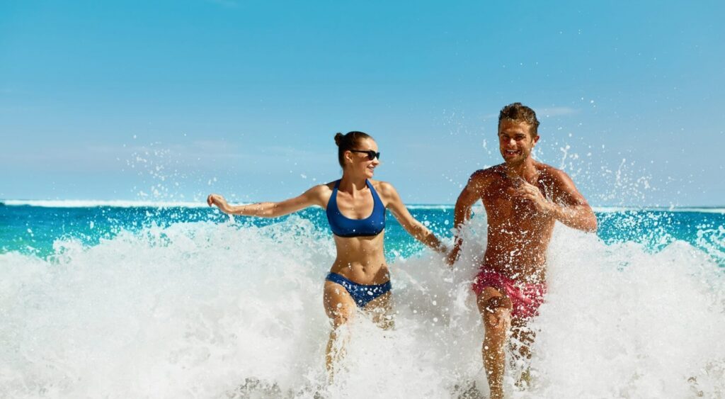 Coppia felice che corre in mare tra le onde.